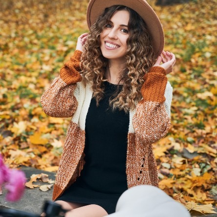 cheerful-young-woman-sitting-on-autumn-street-2023-11-27-05-05-49-utc